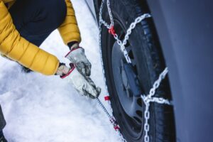 Man putting the snow chains on his car